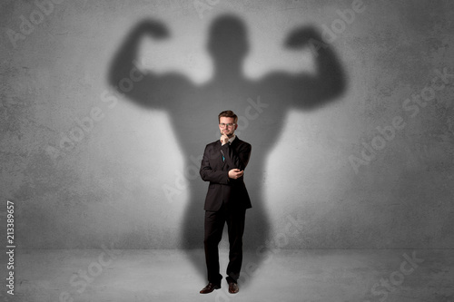 Obraz na plátně Lovely serious businessman standing with a muscular powerful shadow behind his b