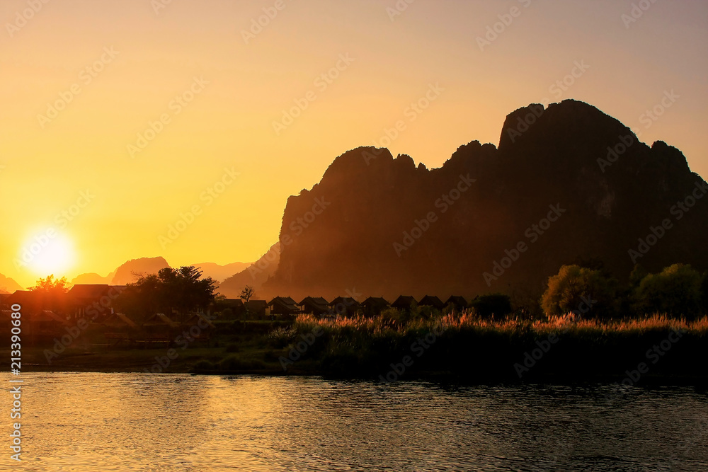 Sunset over Nam Song River with silhouetted rock formations in Vang Vieng, Laos