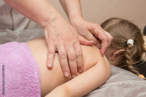 the masseur gives the child a back massage