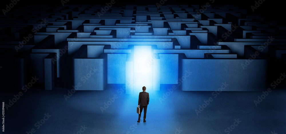 Lost businessman standing at the dark labyrinth with illuminated door
Lost businessman standing at the dark labyrinth with illuminated door