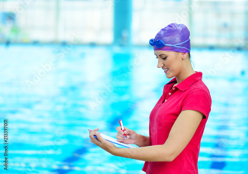 Pretty trainer looking at stopwatch at the pool