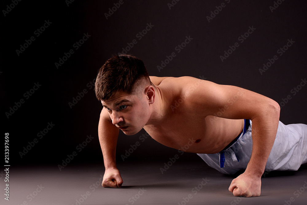 An athlete doing push-ups on fists on the gray background in the studio An athlete doing push-ups on fists on the gray background in the studio