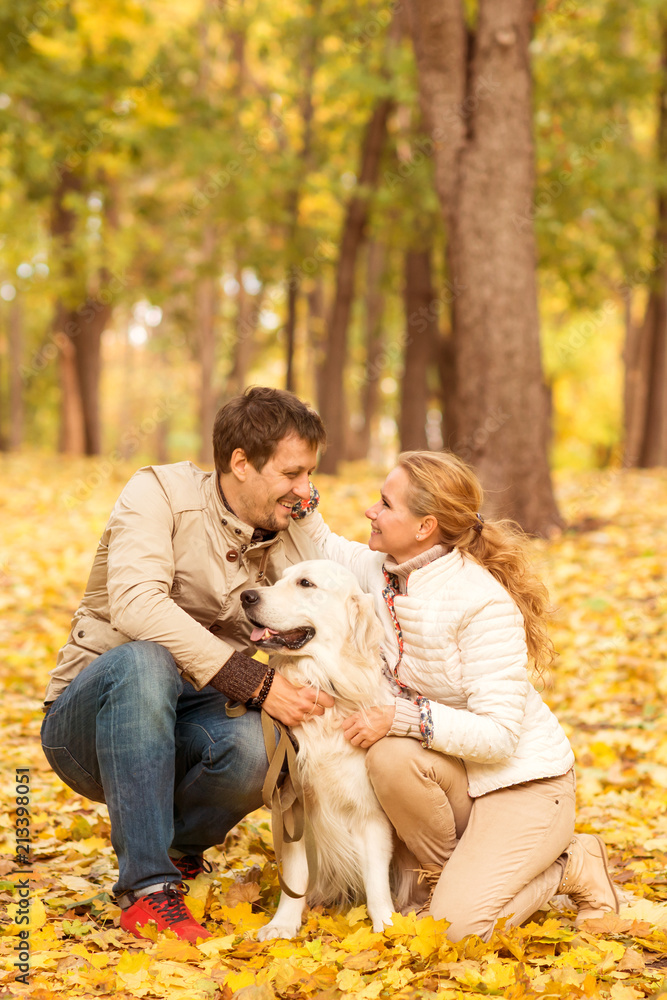 Family portrait of  young man and woman  with his dog Labrador in an autumn park.