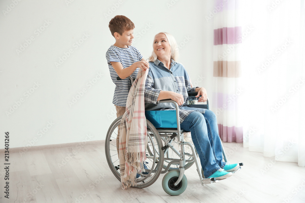 Little boy taking care of mature woman in wheelchair indoors Little boy taking care of mature woman in wheelchair indoors