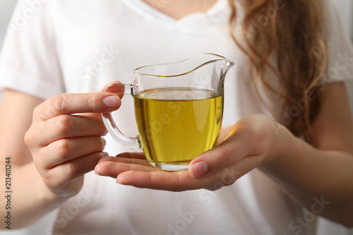 Young woman holding jug of fresh olive oil, closeup
