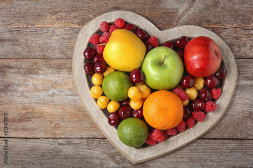 Fototapeta Naklejka Na Ścianę i Meble -  Heart shaped plate with fresh fruits on wooden table, top view. Cardiac diet