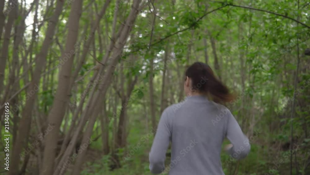 Young woman running through the woods, looking back. Young woman running through the woods, looking back.