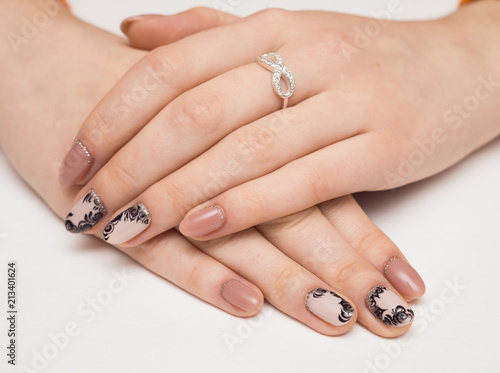 Hands with manicured nails covered with pink nail polish on fur background