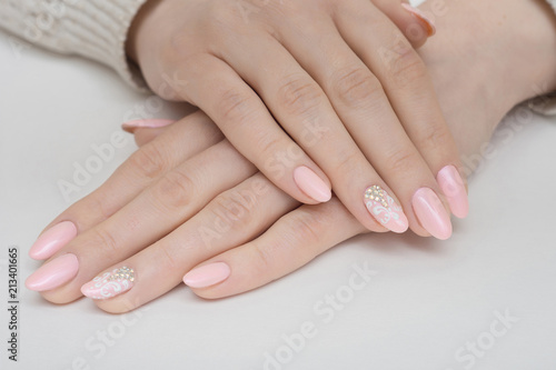 Hands with manicured nails covered with pink nail polish on fur background