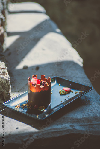 Fototapeta Naklejka Na Ścianę i Meble -  exclusive chocolate cake like tower with fruits served on black plate, product photography for patisserie, dessert for castle 