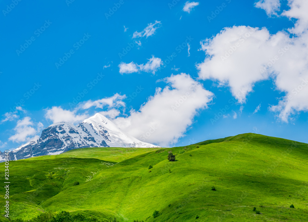 Idyllic landscape with blue sky, fresh green meadows and snowcapped mountain top. Svanetia region, Georgia Idyllic landscape with blue sky, fresh green meadows and snowcapped mountain top. Svanetia region, Georgia