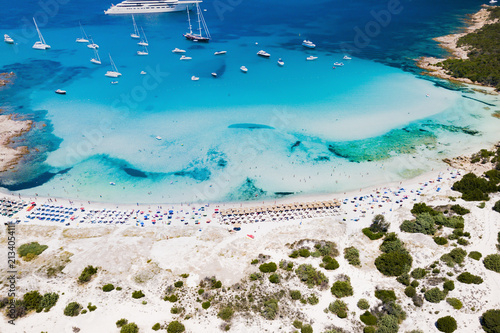 Aerial view of an emerald and transparent mediterranean sea with a white beach and some yachts. Gulf of the Great Pevero,Sardinia, Italy.