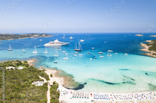 Aerial view of an emerald and transparent mediterranean sea with a white beach and some yachts. Gulf of the Great Pevero,Sardinia, Italy. photo