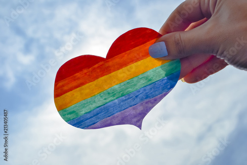 LGBT day concept, hand holds a heart painted like a LGBT flag photo