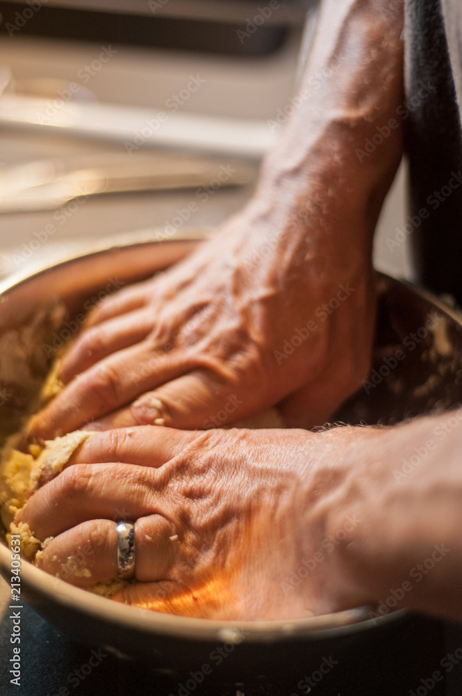A man prepares pastry in a metal bowl.  The process of making a pie crust.  Vertical shot with shallow depth of field.