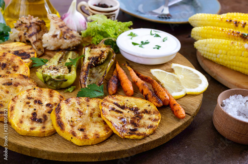 Grilled vegetables, fresh herbs, sauce on a wooden tray. Healthy food. A delicious appetizer.