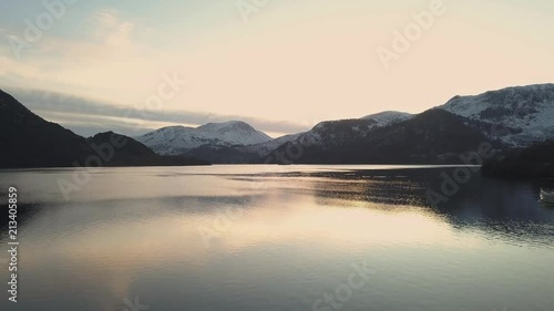 Wallpaper Mural Drone shot of a boat crossing a lake surrounded by snowy mountains at sunset. Creating ripples in the water as the boat crosses the lake. Sunset reflections on water. Torontodigital.ca