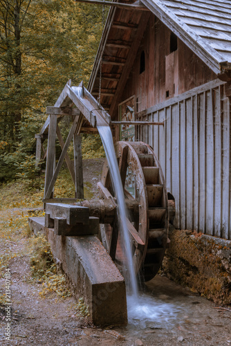 Alte Mühle antique wooden grain mill with large water wheel and flowing water with motion blur in the forest