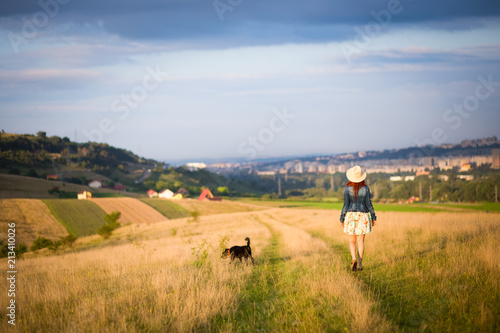 Girl walking in meadow with dog,summer holiday background