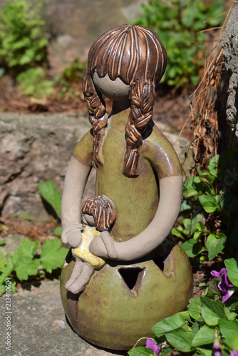 Girl with doll pottery statue. Vintage art studio design