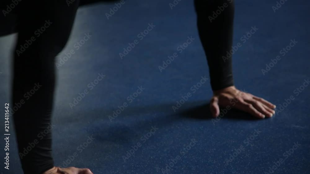 Man doing push-ups in gym, blue background, close-up Man doing push-ups in gym, blue background, close-up