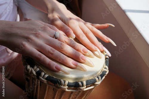 Female Hands with Long Fingernails on a djembe drum