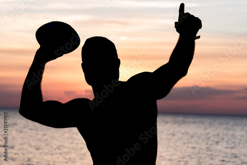 Silhouette of athlete with ball on sunset beach photo