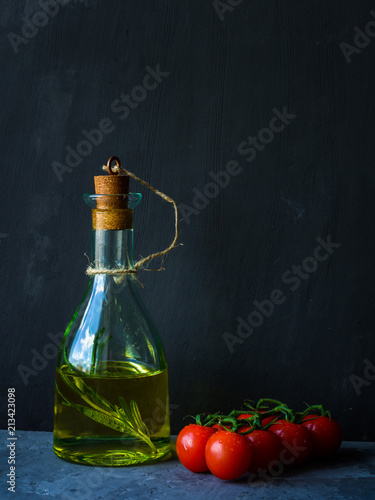 Fototapeta Naklejka Na Ścianę i Meble -  Oil bottle and cherry tomatoes on dark stone background.