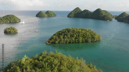 Drone shot of tropical islands or islet with a boat on the background floating towards the horizon. photo