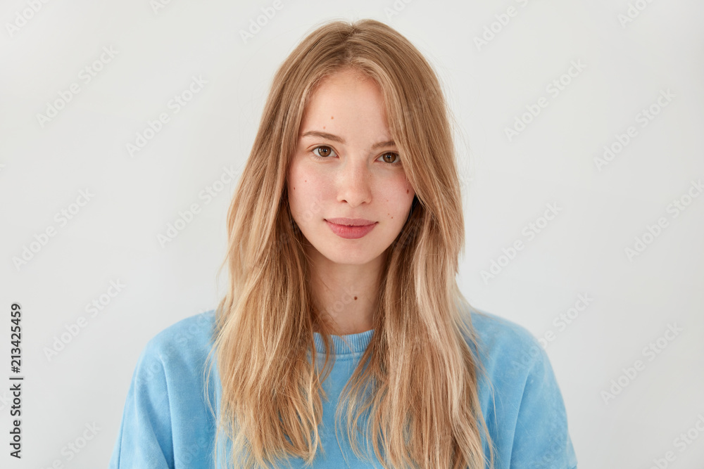 Horizontal shot of pleasant looking European female with satisfied expression, has lovely appearance, dressed in casual blue sweater, isolated over white background. People and tenderness concept Horizontal shot of pleasant looking European female with satisfied expression, has lovely appearance, dressed in casual blue sweater, isolated over white background. People and tenderness concept