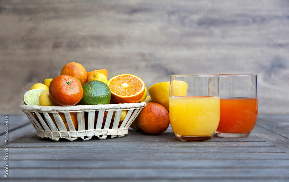 Citrus fruit and juice in a wooden background. Oranges, limes, Tangerines, Chinese oranges, blood oranges and other varieties. High source of vitamin C. Citrus fruit and juice in a wooden background. Oranges, limes, Tangerines, Chinese oranges, blood oranges and other varieties. High source of vitamin C.