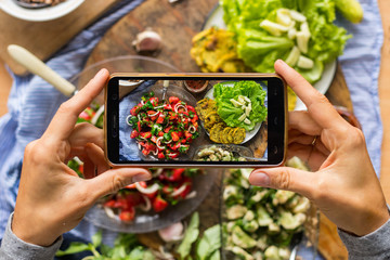 Smartphone food photography of vegetarian lunch or dinner. Woman hands taking phone photo of food in trendy style for social media or blogging.