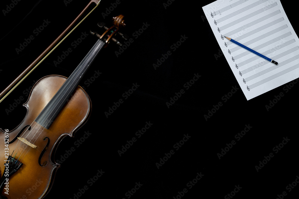 Top view of violin and musical note sheet on the black background Top view of violin and musical note sheet on the black background