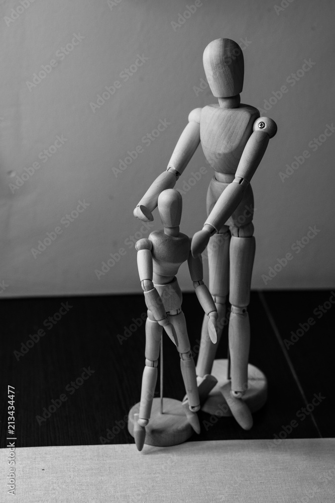 Two wooden movable mannequins of different sizes stand side by side. Shooting close-up.