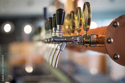 Row of draft beer tab on the top of counter bar in closeup view, time of celebration, selective focus. photo