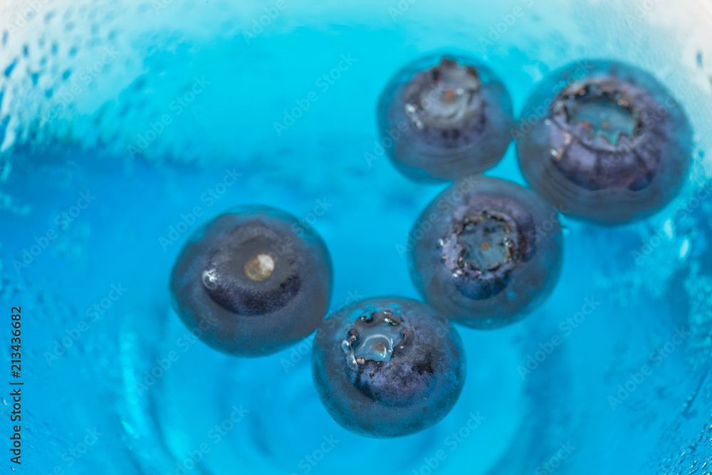 blueberry floating in a cup of blue water blueberry floating in a cup of blue water
