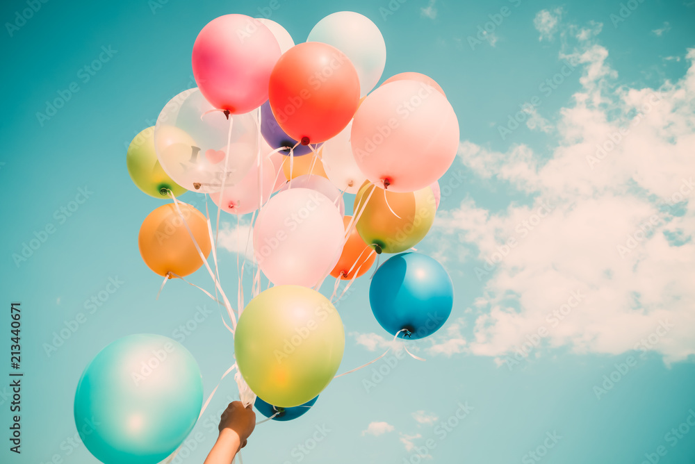 Hand holding multi colored balloons done with a retro vintage instagram filter effect. Hand holding multi colored balloons done with a retro vintage instagram filter effect.
