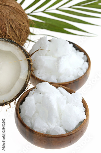 Coconut oil. organic natural solid coconut oil in pieces in round wooden bowls and half fresh coconut and a palm leaf isolated on a white background. 