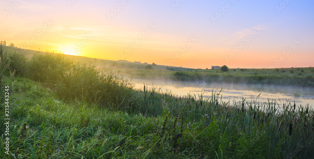 Foggy sunny landscape with river.Beautiful summer scene with rising sun.