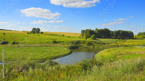 Sunny summer landscape with woods fields river and green hills.