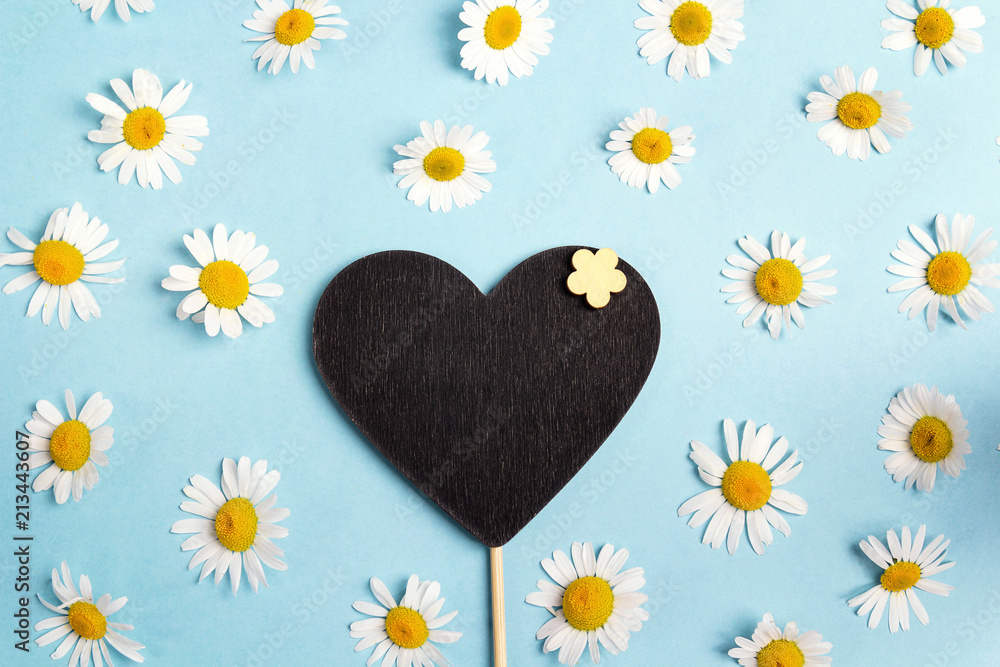 Obraz premium Blank blackboard-heart with chamomiles on blue background.
