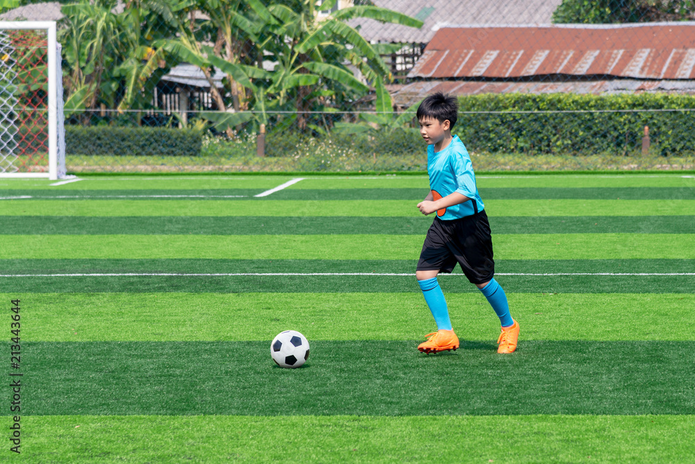Asian boy playing football at the stadium, sports, outdoor activities Asian boy playing football at the stadium, sports, outdoor activities