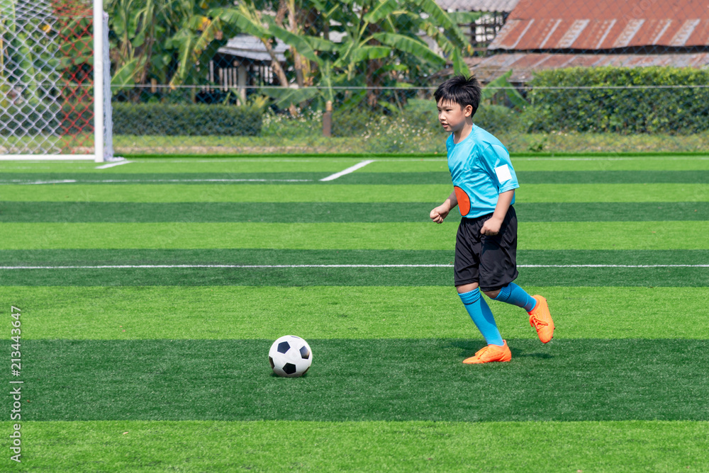 Asian boy playing football at the stadium, sports, outdoor activities Asian boy playing football at the stadium, sports, outdoor activities