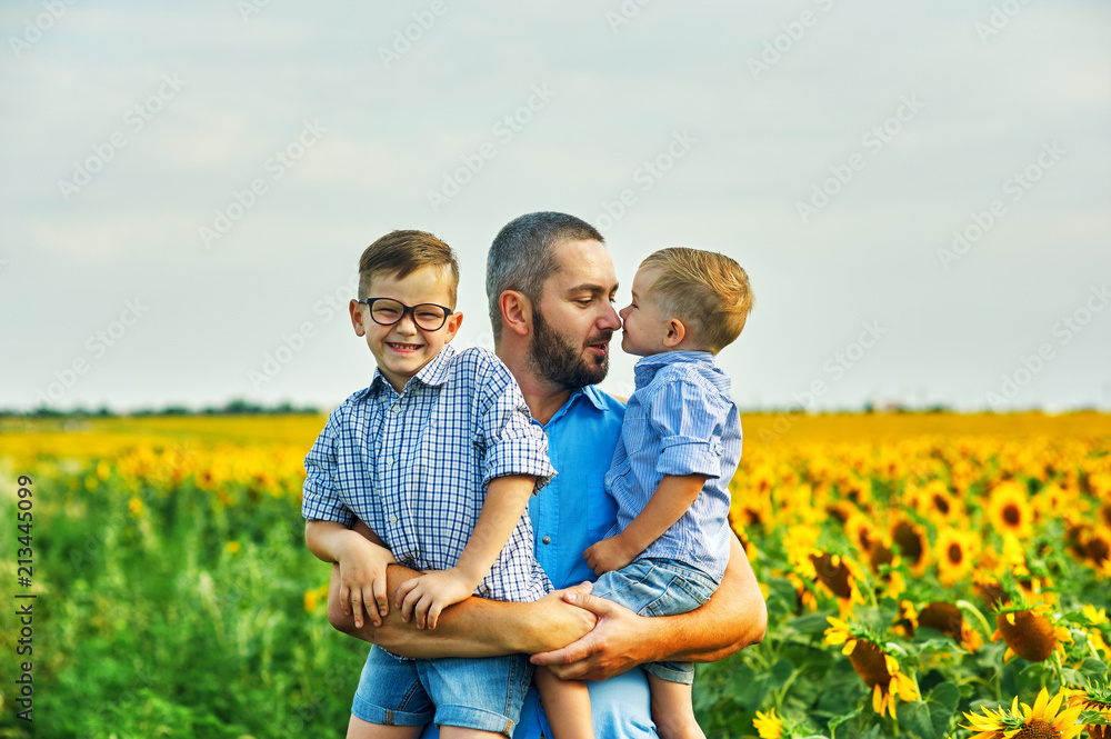 Happy father holding his two sons on a summer walk Happy father holding his two sons on a summer walk