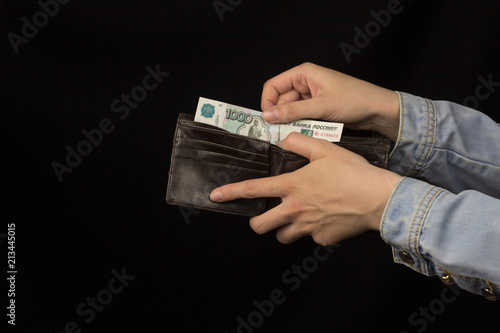 Girl lays Russian money in a purse, close-up, black background, banknote