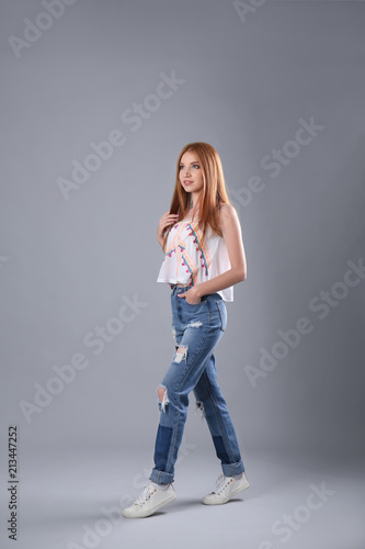 Young woman in stylish jeans on grey background