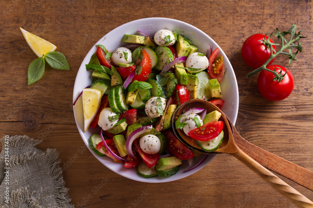 Avocado, tomato, cucumber salad with mozzarella cheese. View from above, top studio shot Avocado, tomato, cucumber salad with mozzarella cheese. View from above, top studio shot