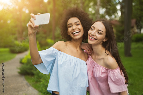 Two cute young women taking selfie in park