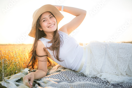 Happy asian woman sitting in meadows with sunset