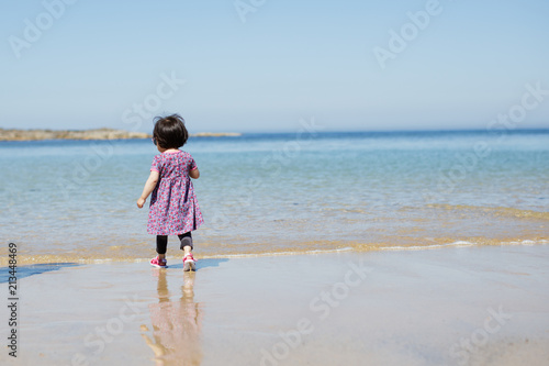 baby girl wearing sunglasses running on the summer beach © M-image